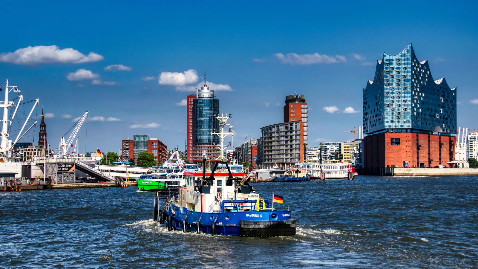 A workboat on the Elbe with Hamburg’s waterfront skyline and Elbphilharmonie behind