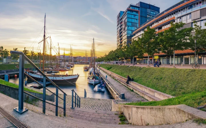 Sailboats in Kiel’s Germaniahafen beside modern waterfront buildings at sunset