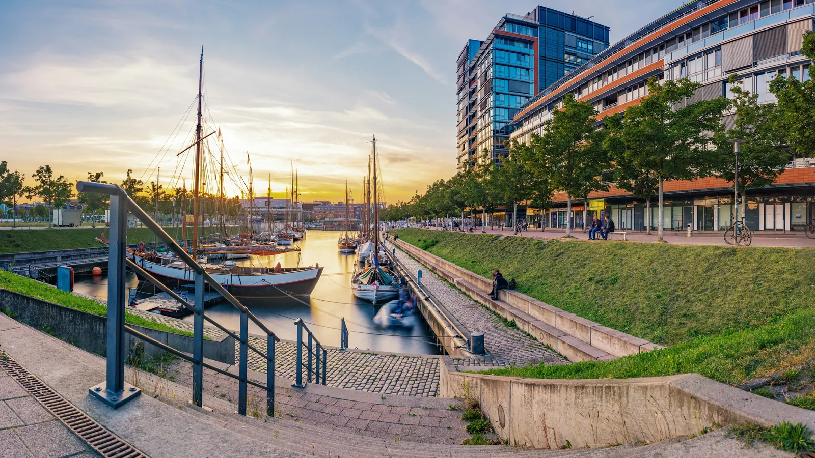 Sailboats in Kiel’s Germaniahafen beside modern waterfront buildings at sunset
