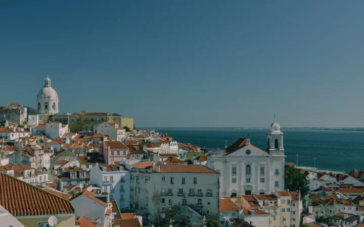 Alfama’s red-tiled rooftops and churches overlooking the Tagus River in Lisbon