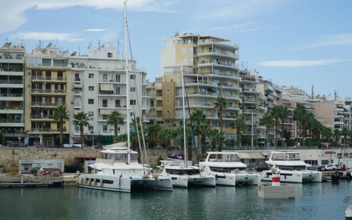 Boats in a Piraeus marina with apartment buildings along the waterfront