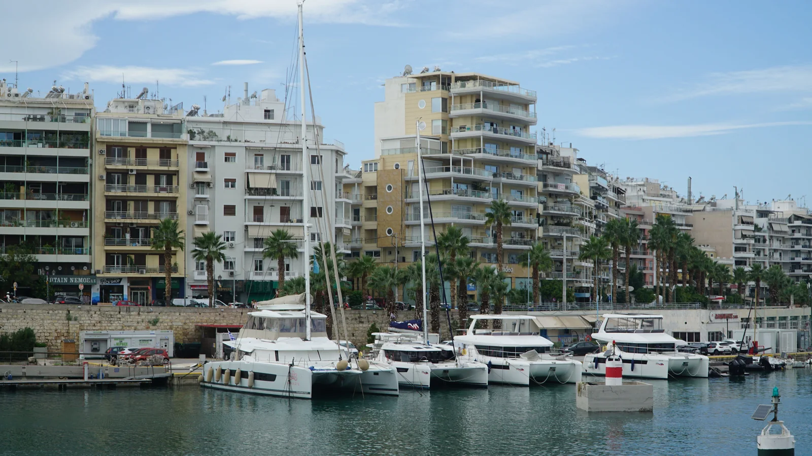 Boats in a Piraeus marina with apartment buildings along the waterfront