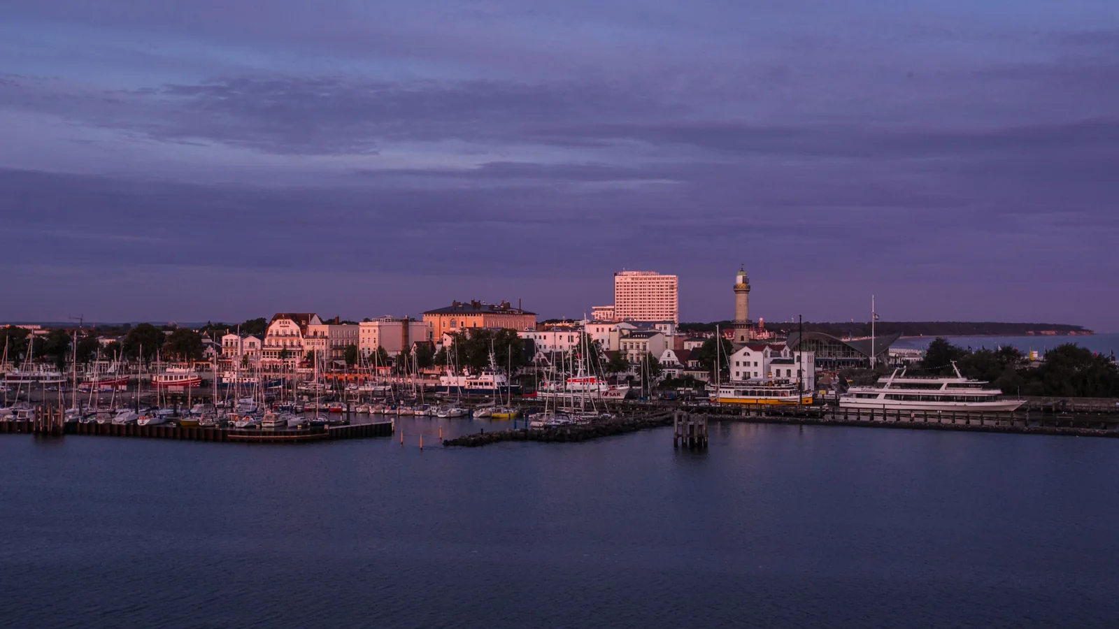 Warnemünde waterfront, marina and lighthouse across the harbor at dusk